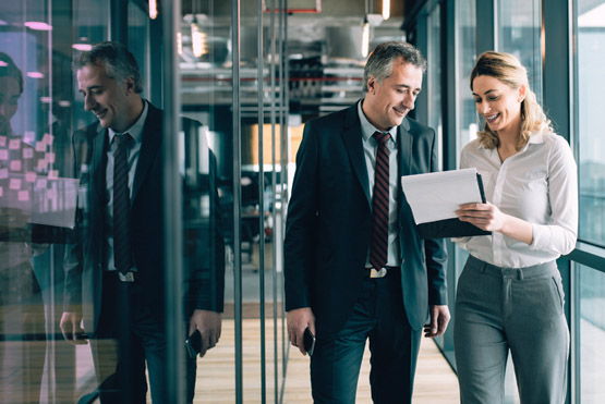 Insurance professionals waliking down a corridor and discussing a claims management report